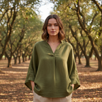 Woman wearing a green blouse standing in an orchard