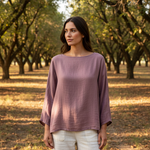 Woman wearing a purple top standing in an orchard