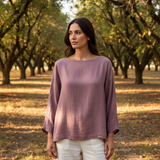 Woman wearing a purple top standing in an orchard