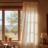 Room with large window showing a scenic view of trees and mountains, with light filtering through sheer curtains.
