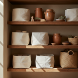 Wooden shelves with various ceramic and woven containers in a warm, natural setting.