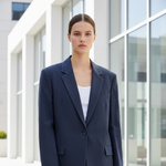Woman in a navy blazer holding a matching handbag in front of a modern building.