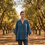 Woman standing in an orchard wearing a blue shirt