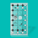Quilting ruler with grid lines and measurements on a teal background