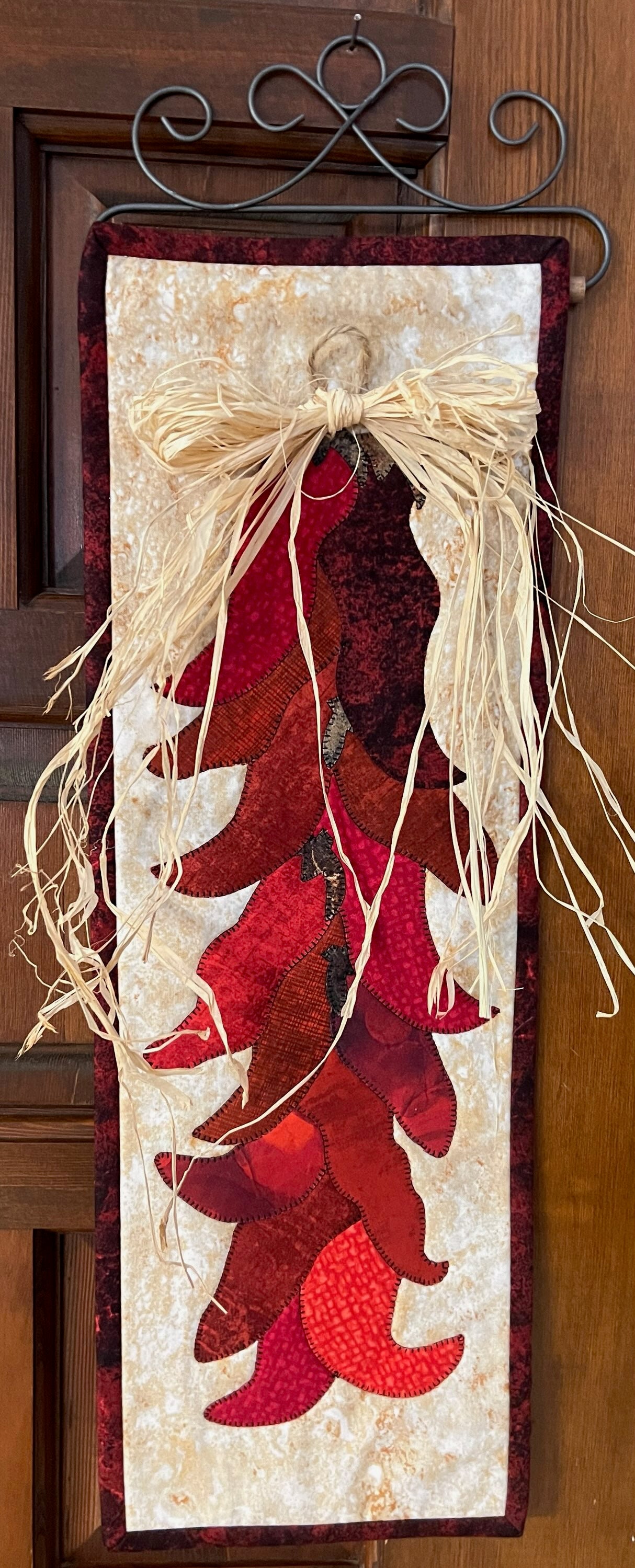 Decorative wall hanging with red chili peppers and a bow on a wooden background