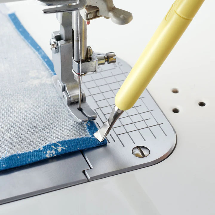 Sewing machine with a foot presser and a yellow tool on a white background