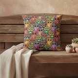Colorful owl patterned pillow on a wooden bench with a beige wall background
