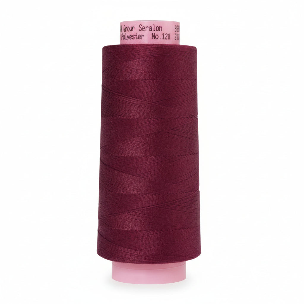 Spool of dark purple thread on a white background