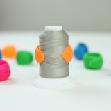 Spool of gray thread with orange ends on a white background