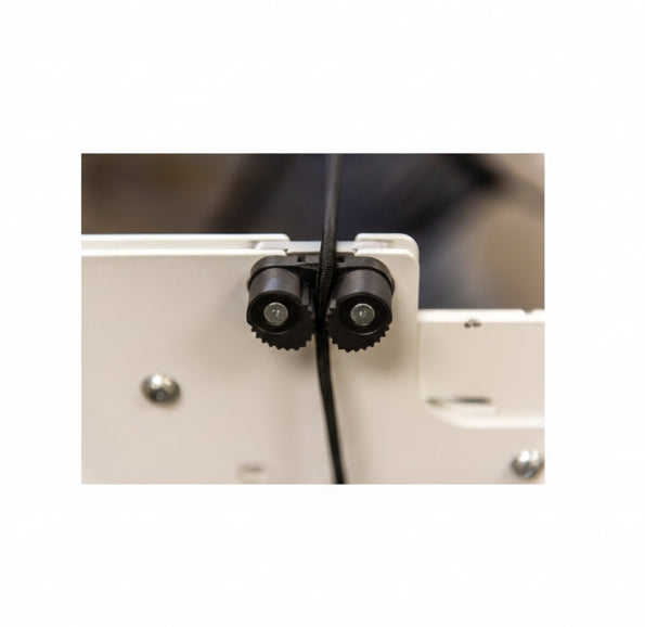 Close-up of a mechanical component with gears and a cable on a blurred background